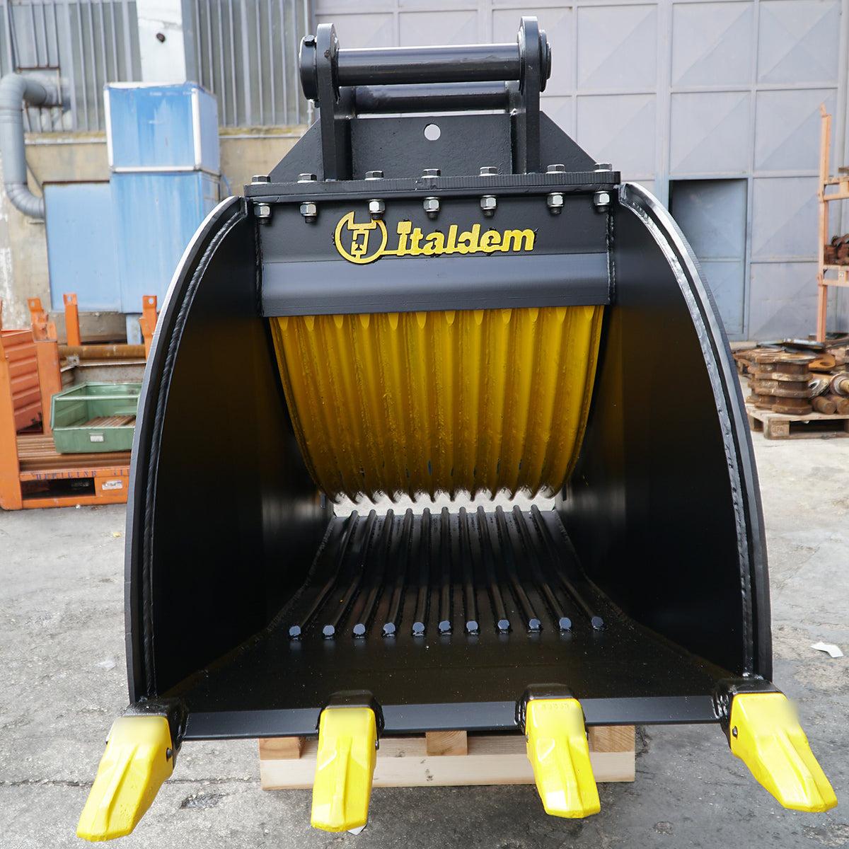 Front view of the Italdem GF 35 crusher bucket on a pallet, showing the crushing jaw and four yellow teeth