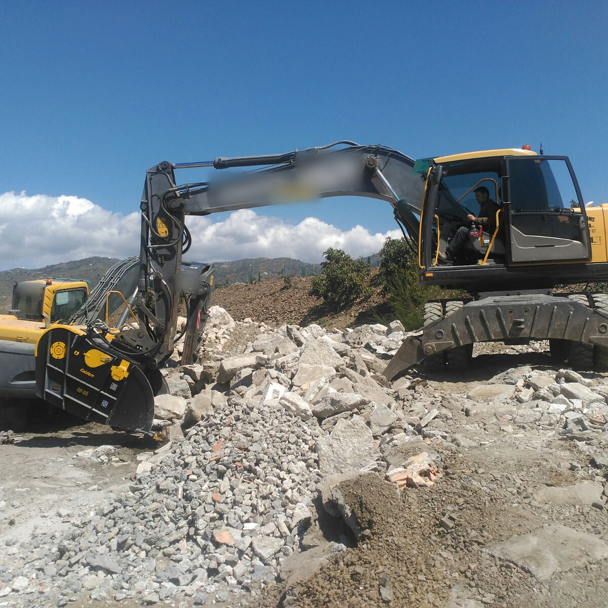 Italdem GF 35 crusher bucket on a wheeled excavator, crushing demolition rubble on site