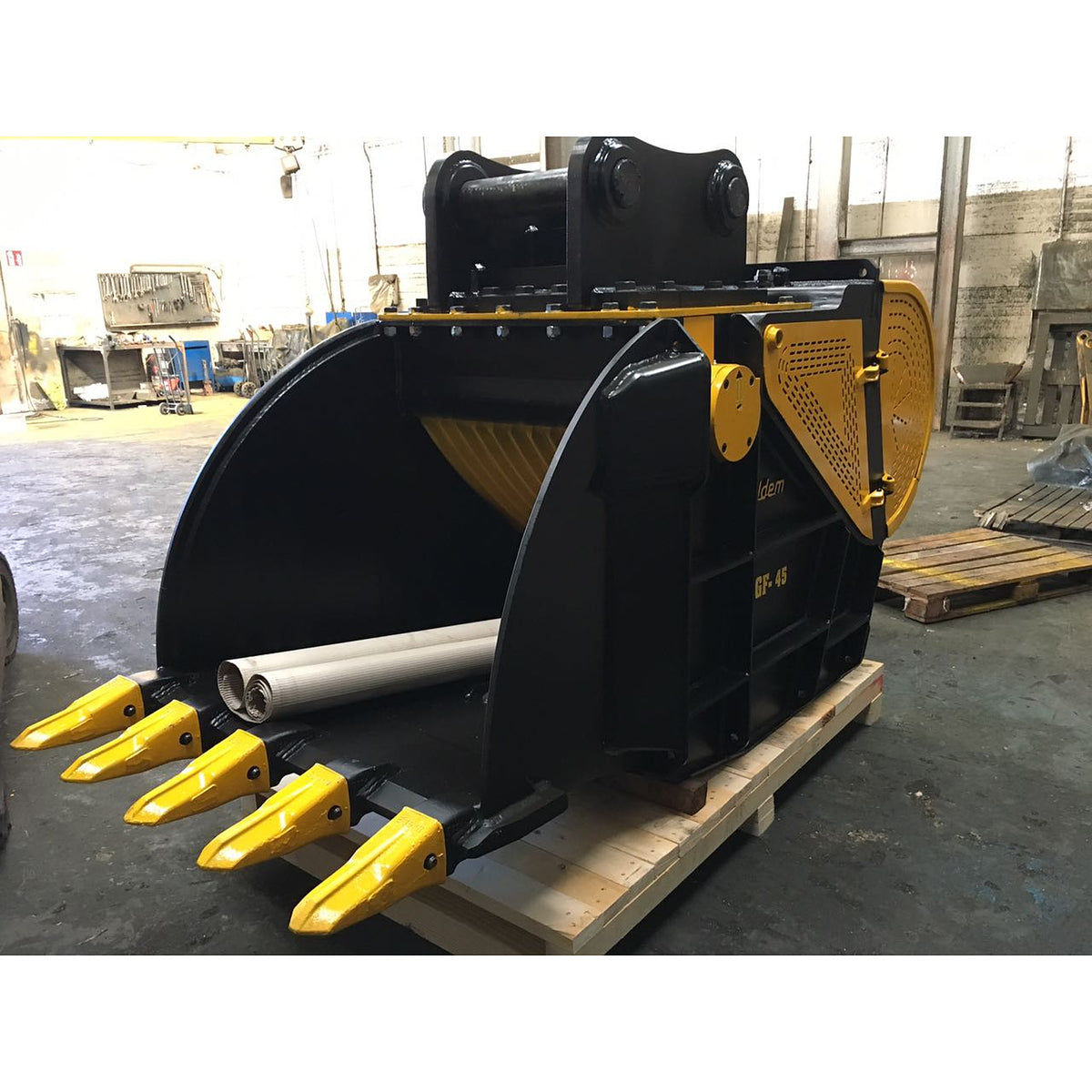 Italdem GF 45 crusher bucket on a wooden pallet in the workshop, five yellow teeth in front